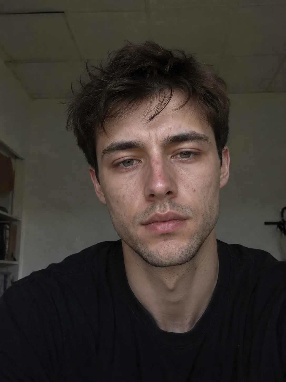 Reference photo: a man in a black shirt taking an indoor selfie